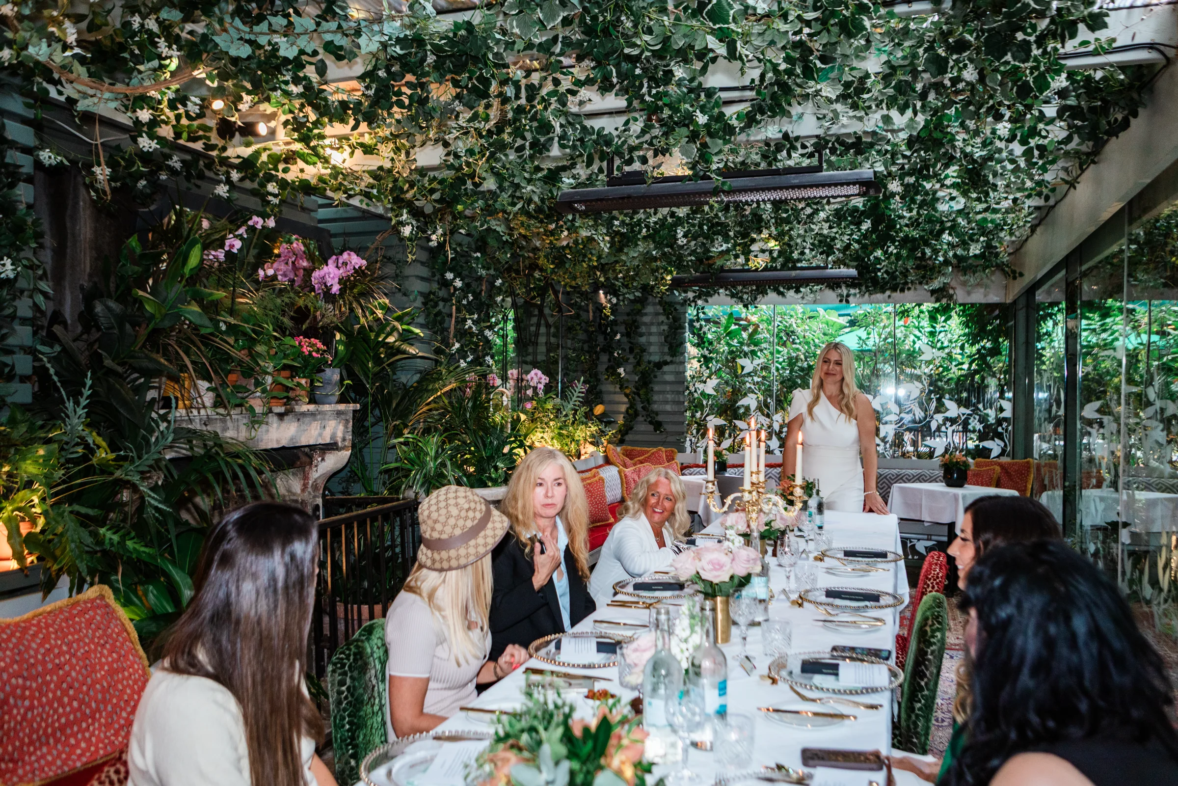 Emily Williams standing at a long table set under greenery at her London event
