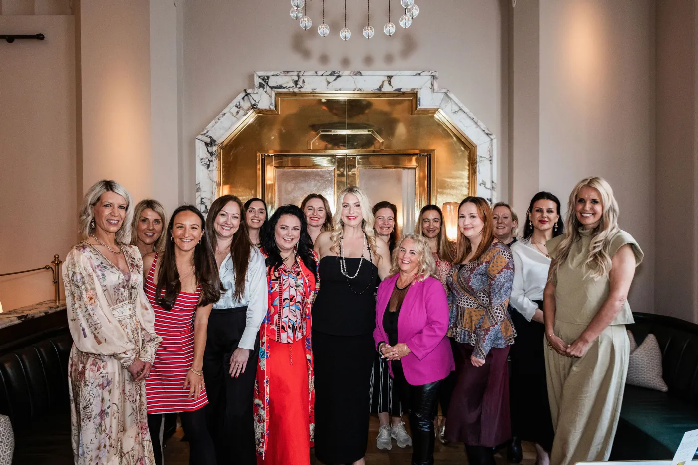 Emily Williams with guests in front of a gold doorway