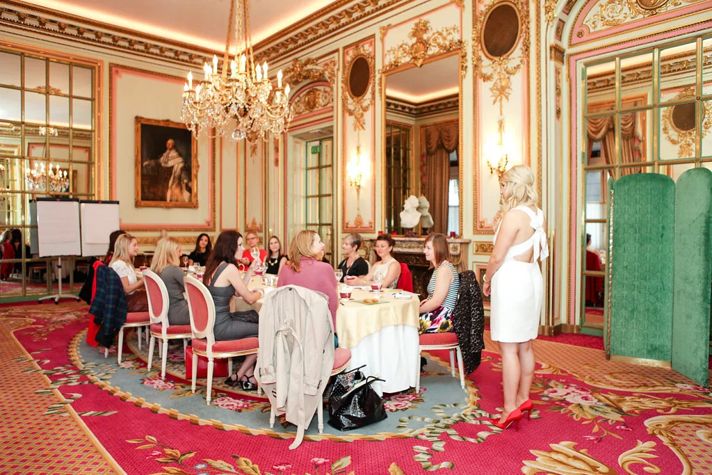 A small group of women around a table in a gilded salon